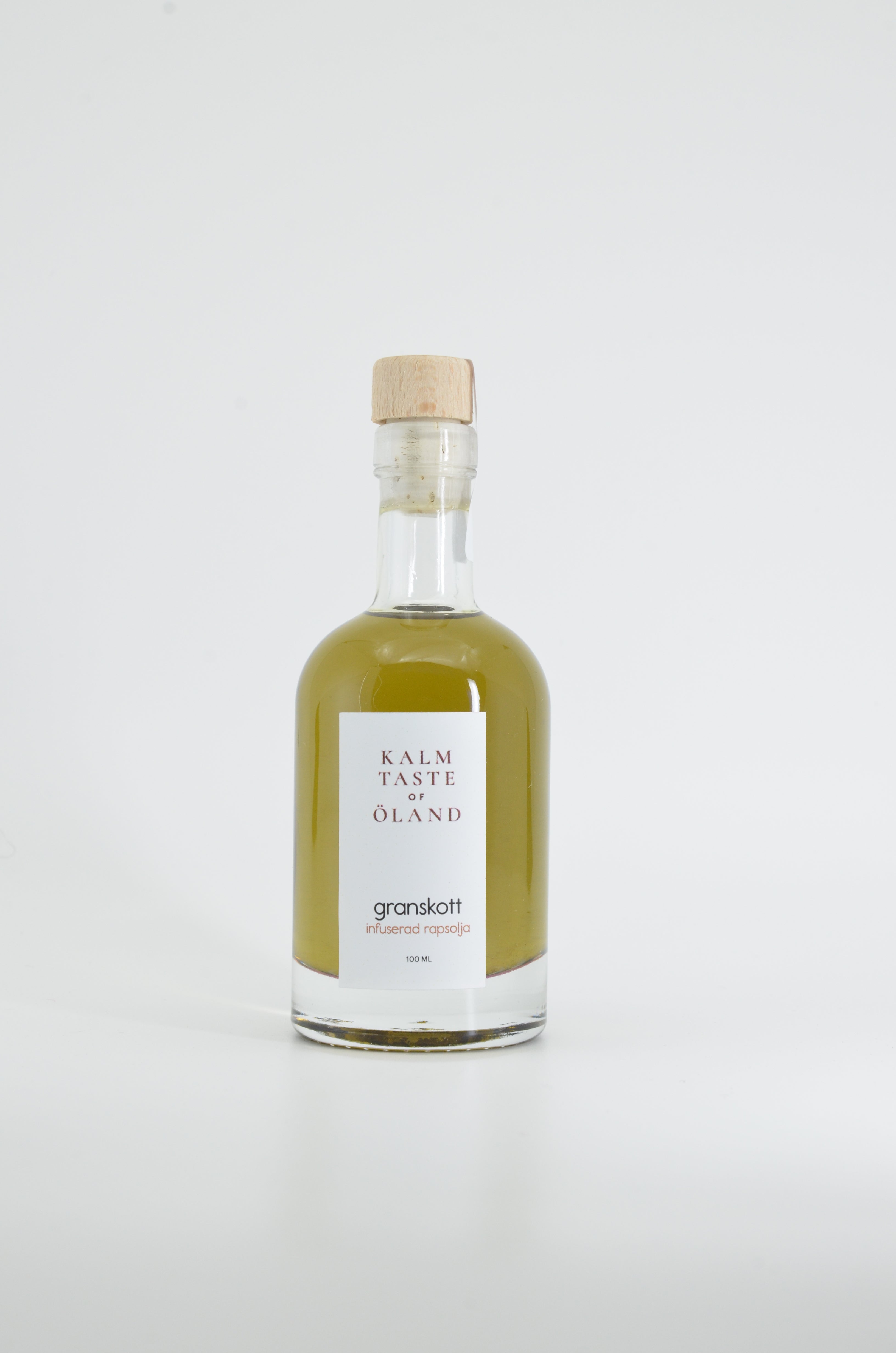 Flaska med Kalm Taste Granskottolja – smaksatt rapsolja med späda granskott, småskaligt producerad i Kastlösa på Öland utan tillsatser eller bekämpningsmedel.