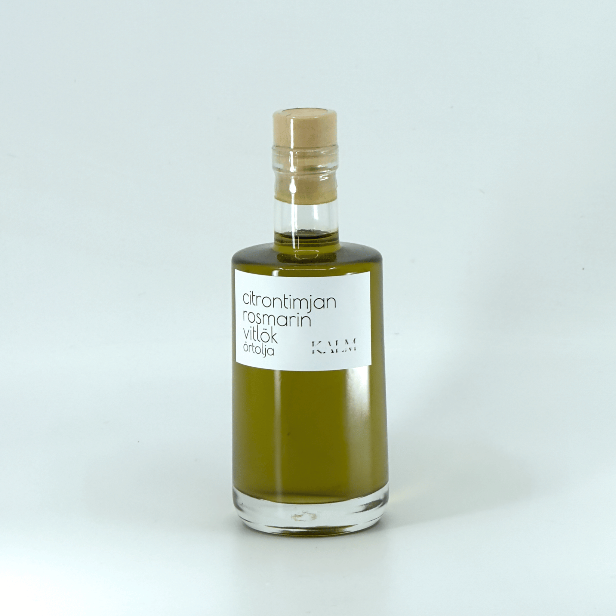 Flaska med Kalm Taste örtolja smaksatt med citrontimjan, rosmarin och vitlök – småskaligt producerad på Öland utan tillsatser eller bekämpningsmedel.