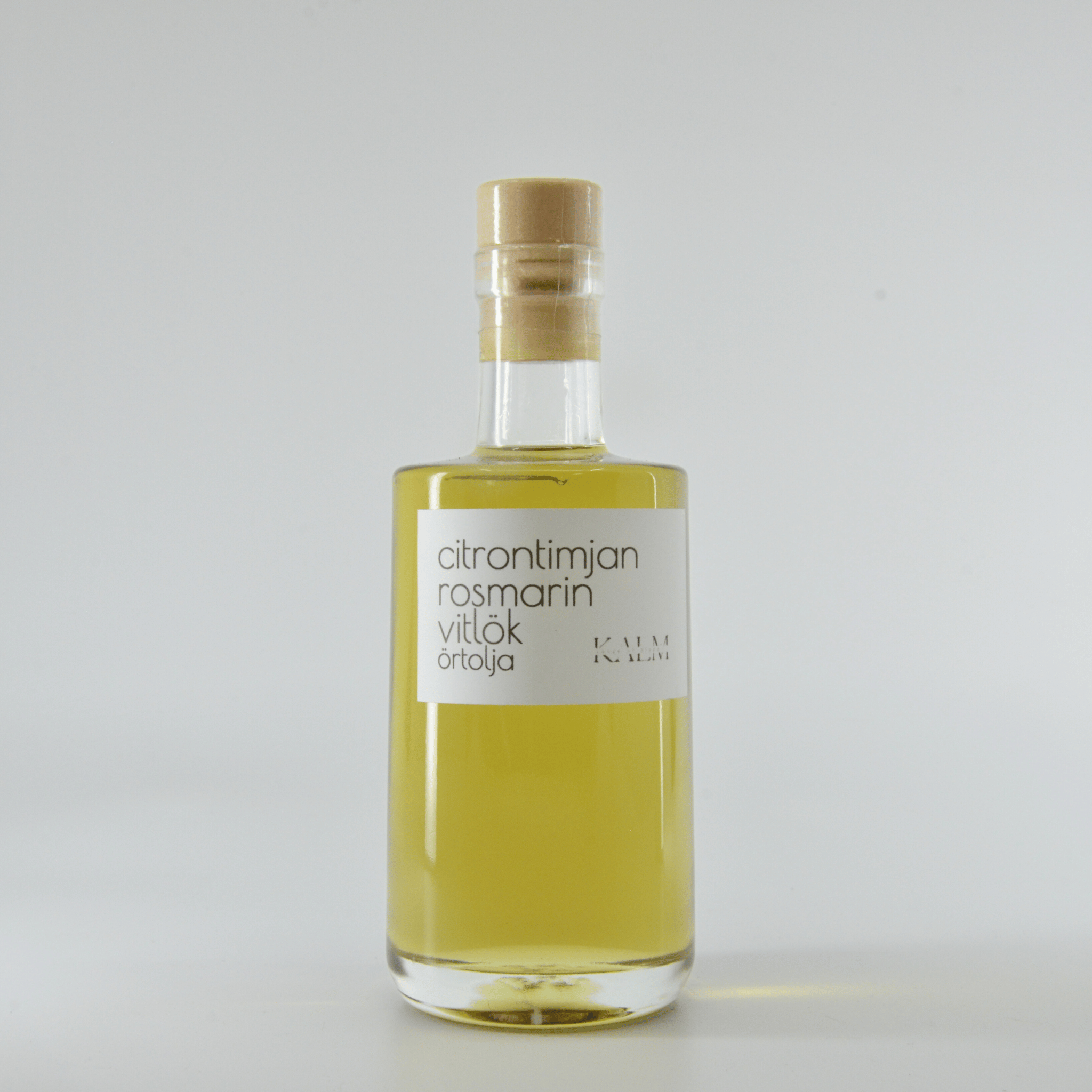 Flaska med Kalm Taste örtolja smaksatt med citrontimjan, rosmarin och vitlök – småskaligt producerad på Öland utan tillsatser eller bekämpningsmedel.
