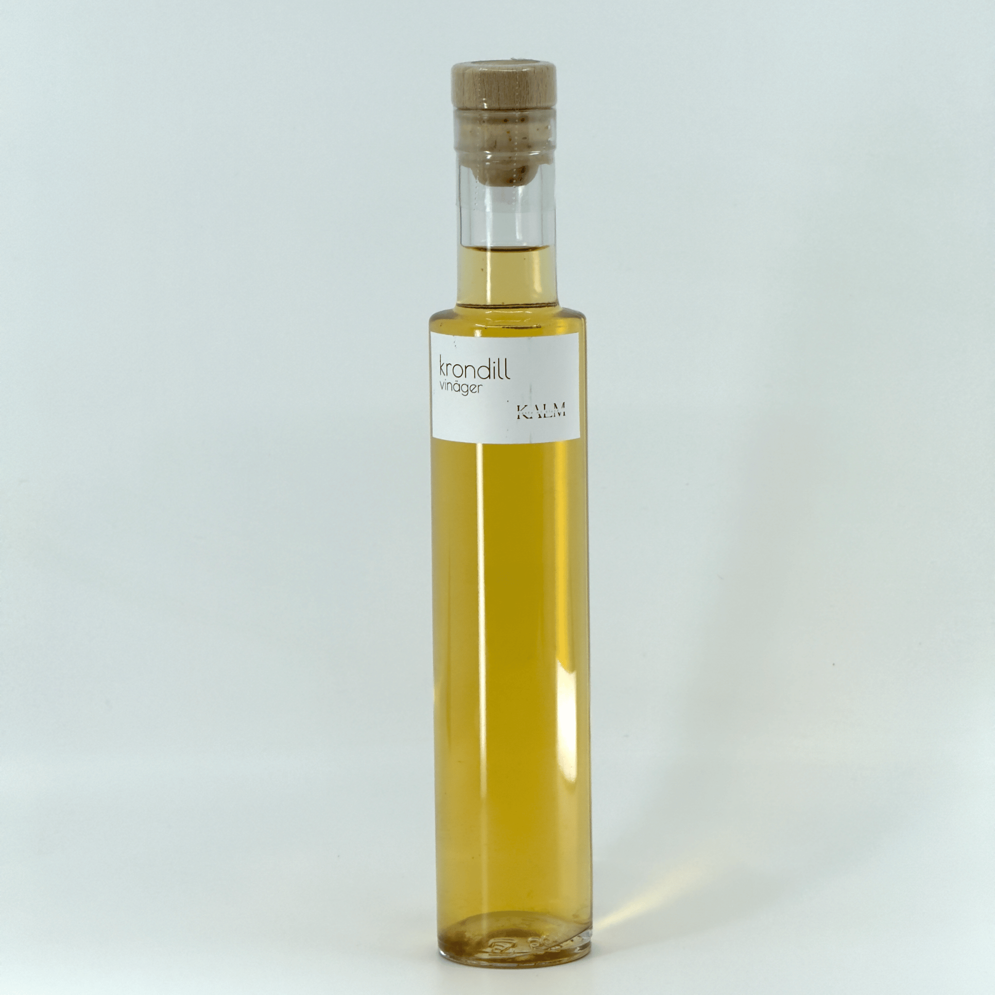 Flaska med Kalm Taste Krondillsvinäger – naturligt ofiltrerad och opastöriserad vinäger lagrad med färsk krondill från Öland, frisk och aromatisk.