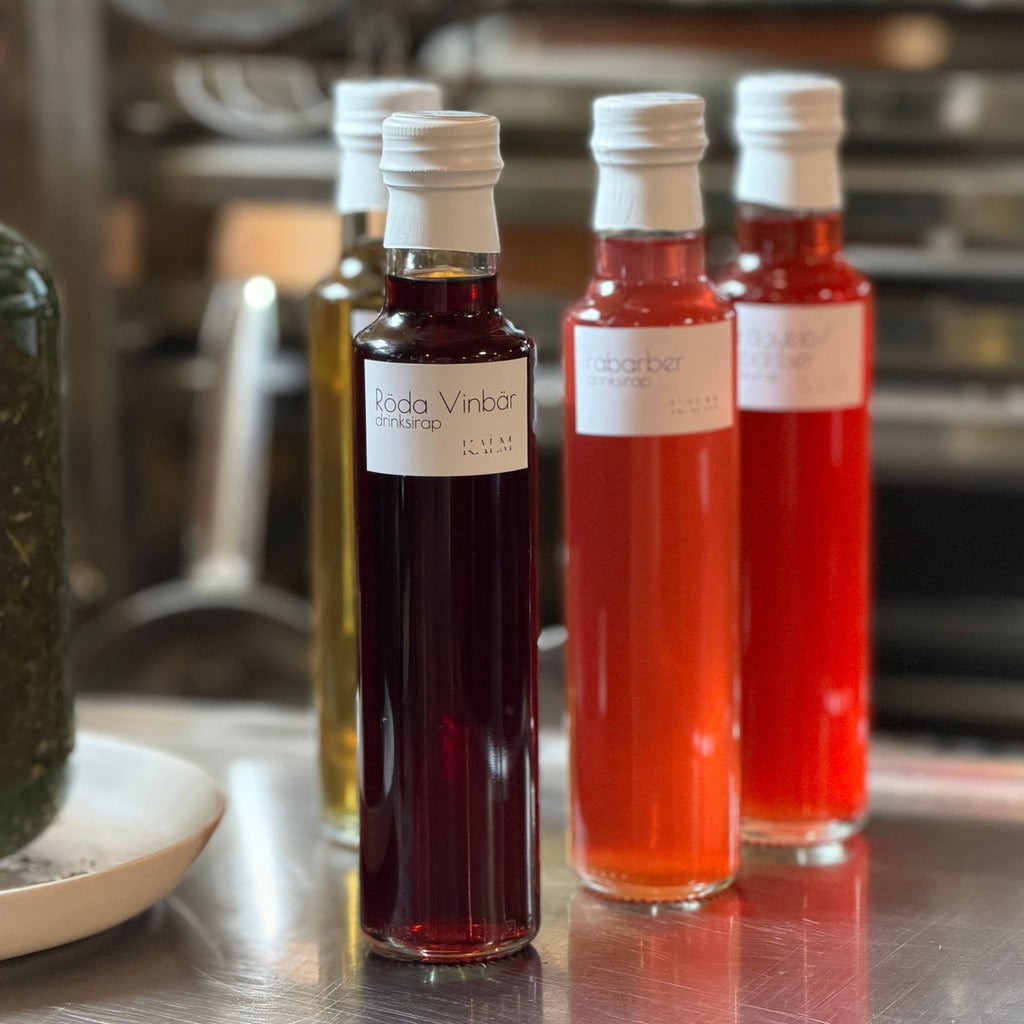 Flaska med handgjord röda vinbärdrinksirap från Kalm Taste Öland för drinkar, mocktails, spritz och alkoholfria sommardrycker.
